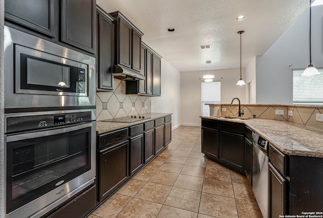 kitchen with a textured ceiling, a wealth of natural light, stainless steel appliances, and sink