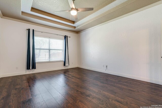 spare room with a tray ceiling, ceiling fan, dark hardwood / wood-style flooring, and a textured ceiling