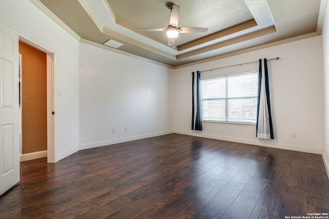 empty room with crown molding, a textured ceiling, dark hardwood / wood-style flooring, ceiling fan, and a tray ceiling