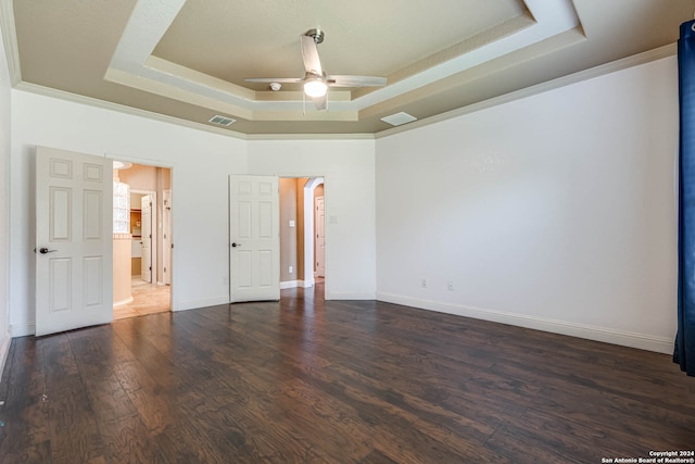 unfurnished room featuring a raised ceiling, ceiling fan, ornamental molding, and dark wood-type flooring