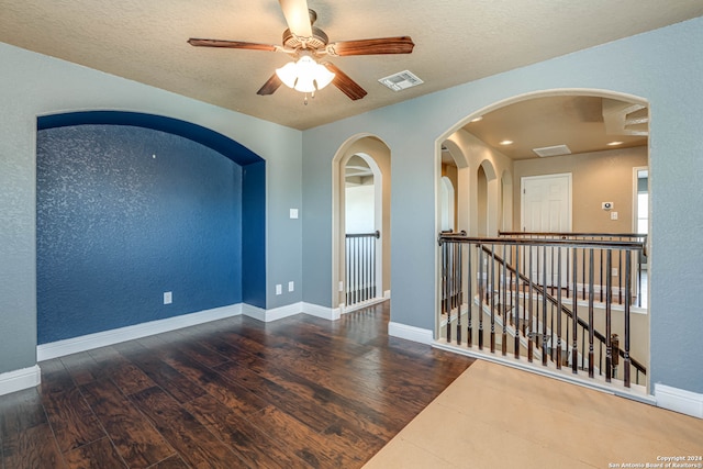 spare room with dark wood-type flooring, a textured ceiling, and ceiling fan