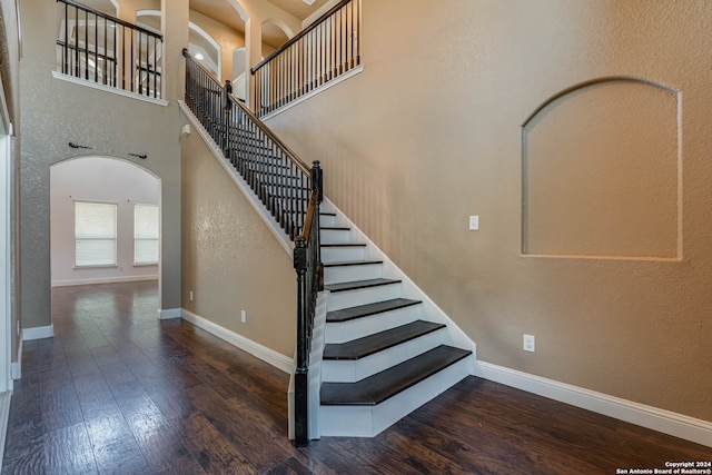 stairs with a towering ceiling and hardwood / wood-style floors