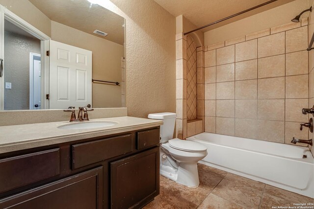 full bathroom featuring toilet, tiled shower / bath combo, a textured ceiling, and vanity