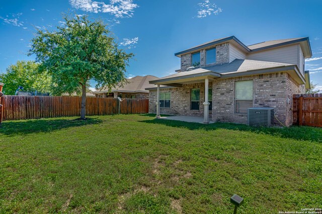 back of property with central air condition unit, a yard, and a patio