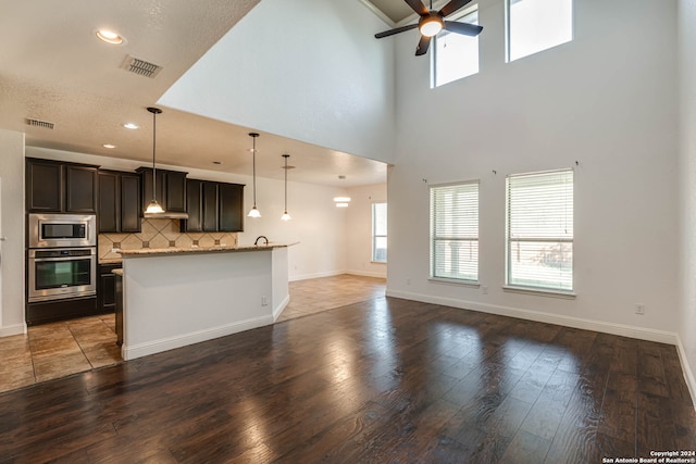 kitchen featuring stainless steel appliances, hardwood / wood-style floors, light stone countertops, and ceiling fan