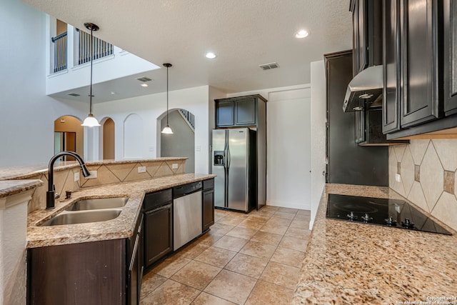 kitchen with light stone countertops, dark brown cabinets, hanging light fixtures, stainless steel appliances, and sink