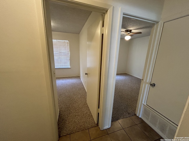 hall featuring a textured ceiling and light colored carpet