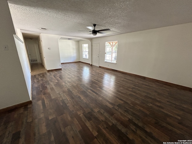 unfurnished living room featuring dark wood-type flooring, a textured ceiling, and ceiling fan