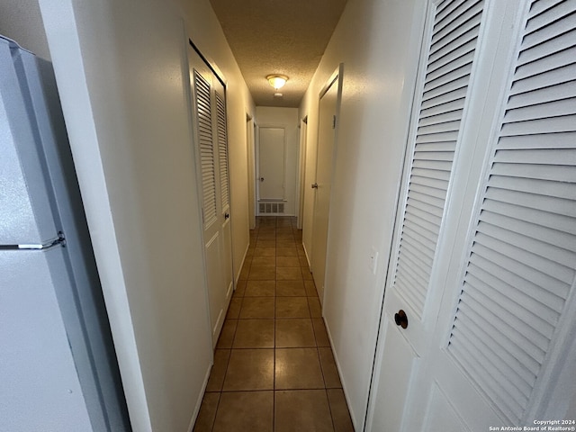 hall with a textured ceiling and tile patterned flooring