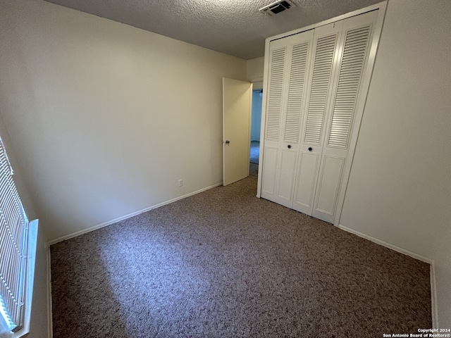 unfurnished bedroom featuring a closet, a textured ceiling, and carpet floors