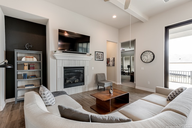 living room with ceiling fan, hardwood / wood-style flooring, a fireplace, and beam ceiling