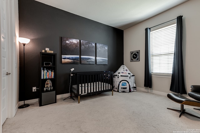 carpeted bedroom featuring a nursery area