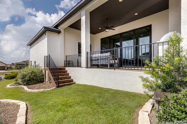 view of exterior entry with ceiling fan and a yard