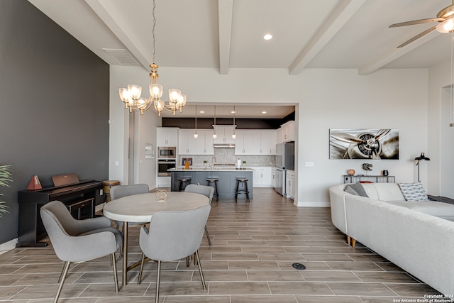 dining area with ceiling fan with notable chandelier, beam ceiling, and light hardwood / wood-style floors