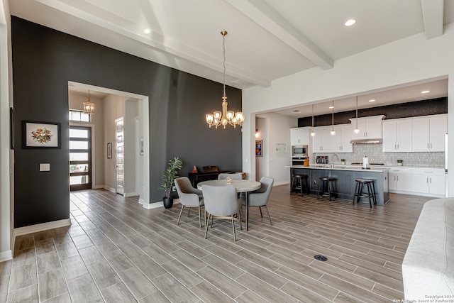 dining area featuring light hardwood / wood-style floors, beam ceiling, a chandelier, and sink