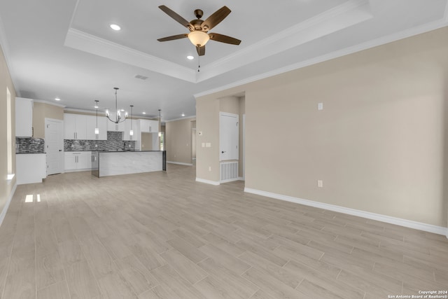 unfurnished living room with light hardwood / wood-style floors, ceiling fan with notable chandelier, a raised ceiling, and crown molding