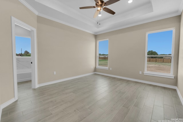 unfurnished room featuring ceiling fan, ornamental molding, light wood-type flooring, and a tray ceiling