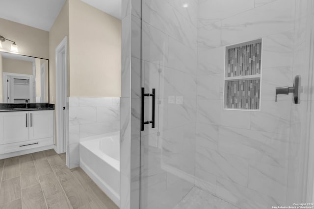 bathroom featuring tile walls, independent shower and bath, wood-type flooring, and vanity