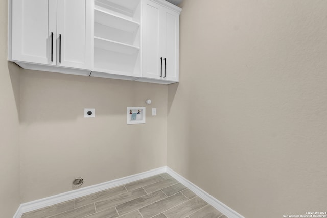 washroom with hookup for a washing machine, gas dryer hookup, light hardwood / wood-style floors, electric dryer hookup, and cabinets