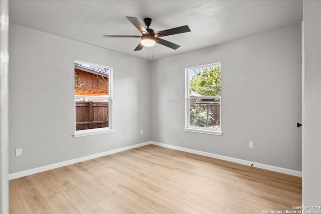 empty room featuring a textured ceiling, a ceiling fan, baseboards, and wood finished floors