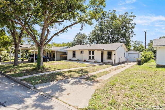 single story home featuring a garage, a front lawn, and an outbuilding