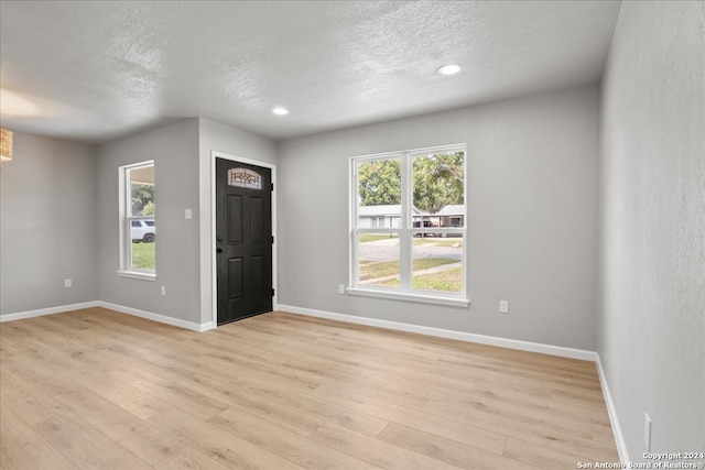 foyer entrance featuring a textured ceiling, light wood-type flooring, and plenty of natural light