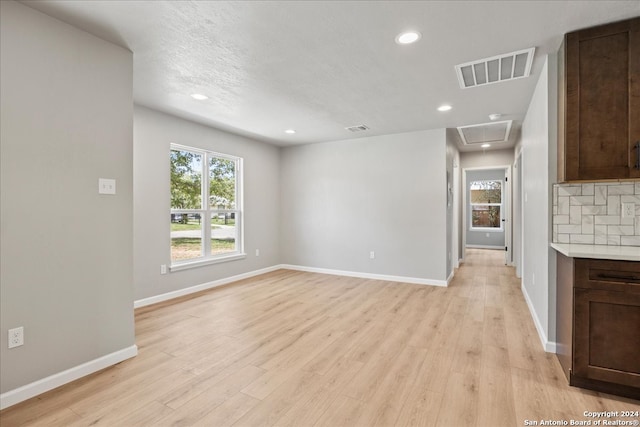 unfurnished living room with light hardwood / wood-style flooring and a textured ceiling