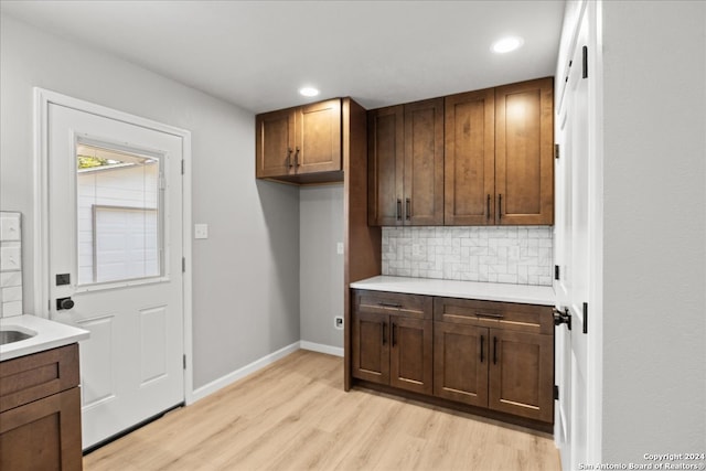 kitchen with light wood-type flooring and backsplash