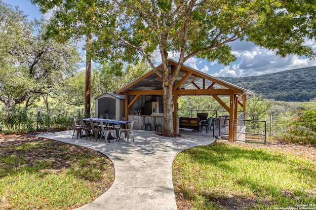 surrounding community with a mountain view, a patio, and a shed