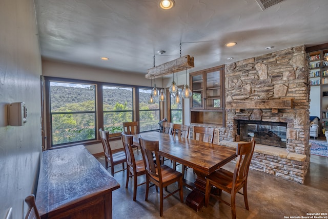 dining room featuring concrete floors and a stone fireplace