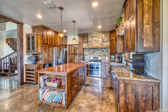 kitchen with decorative light fixtures, a kitchen island, light stone counters, sink, and appliances with stainless steel finishes