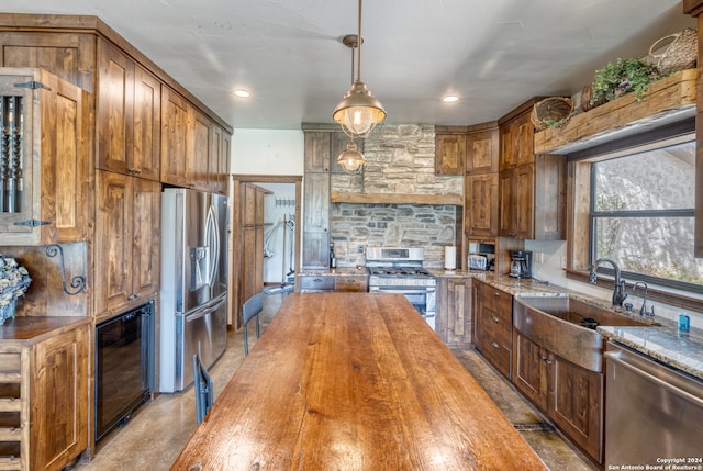 kitchen featuring stainless steel appliances, wooden counters, beverage cooler, sink, and hanging light fixtures