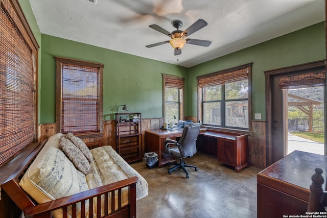 office with wood walls, concrete flooring, and ceiling fan