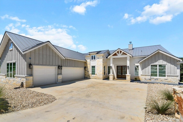 modern farmhouse with french doors, stone siding, board and batten siding, and a standing seam roof