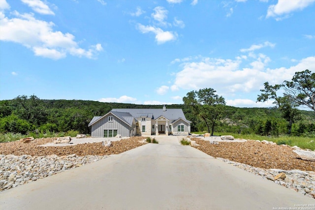 view of front of home with board and batten siding, concrete driveway, and a wooded view