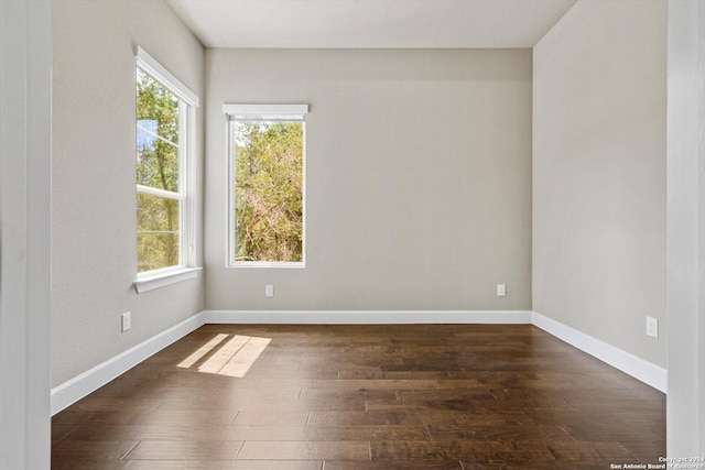 unfurnished room with baseboards and dark wood-style floors