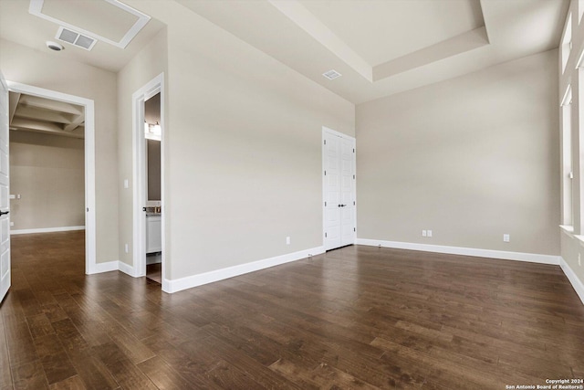 unfurnished room featuring visible vents, baseboards, a raised ceiling, and dark wood-style flooring