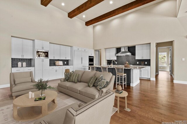 living room with high vaulted ceiling, sink, wood-type flooring, and beam ceiling