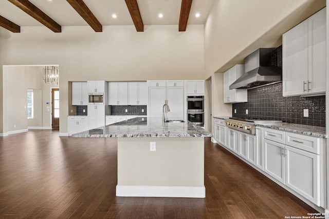 kitchen featuring built in appliances, a high ceiling, wall chimney exhaust hood, and dark wood-style flooring