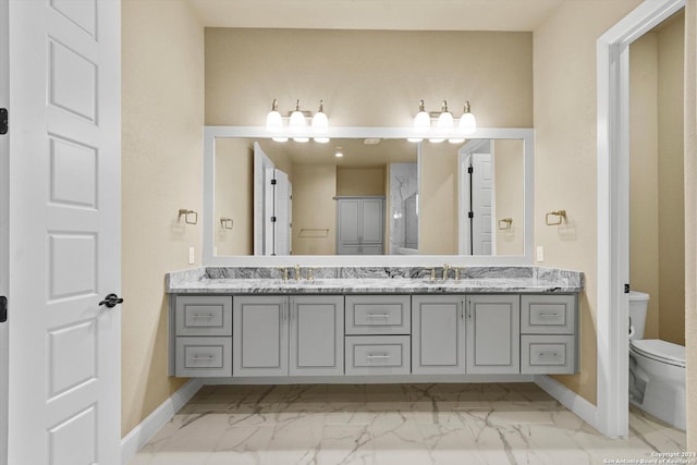 full bathroom with a sink, toilet, marble finish floor, and double vanity