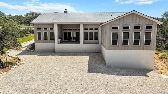 rear view of property with a standing seam roof, board and batten siding, and metal roof