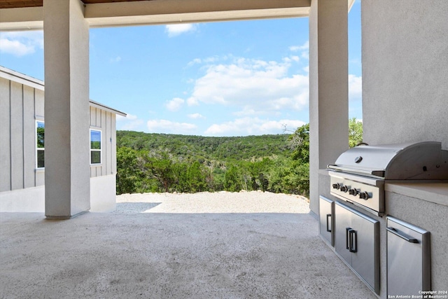 view of patio with grilling area, a wooded view, and area for grilling