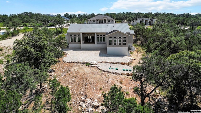 back of house with metal roof and a patio