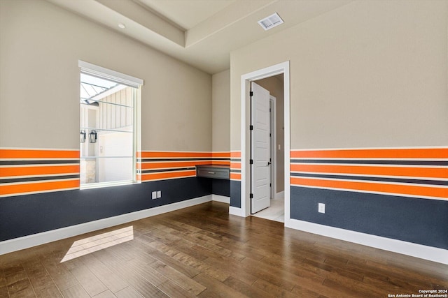 spare room with wood finished floors, visible vents, and baseboards