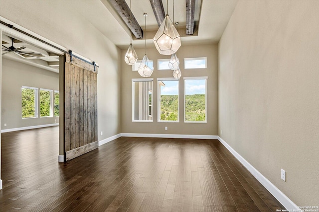 spare room featuring dark wood finished floors, baseboards, a barn door, and a ceiling fan