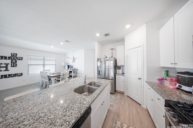 kitchen featuring appliances with stainless steel finishes, light hardwood / wood-style flooring, sink, and light stone countertops