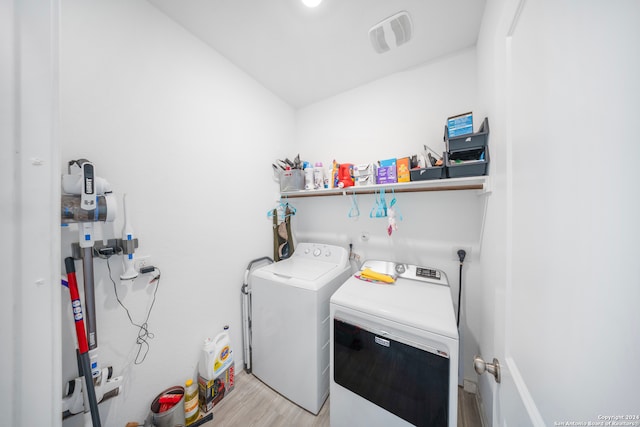 clothes washing area featuring separate washer and dryer and light hardwood / wood-style flooring