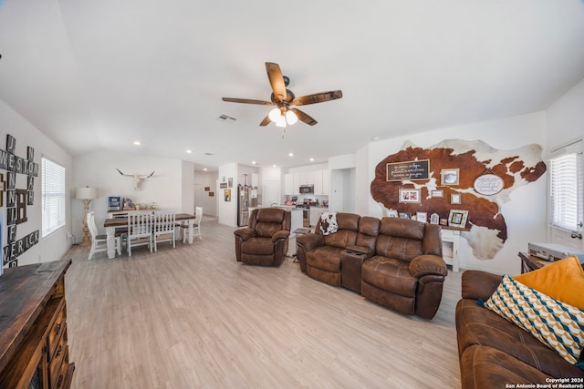 living room featuring lofted ceiling, ceiling fan, and light hardwood / wood-style flooring