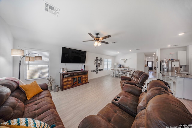 living room featuring light hardwood / wood-style flooring, ceiling fan, and sink