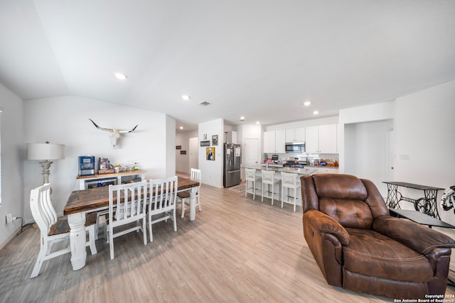 dining room featuring lofted ceiling and light hardwood / wood-style flooring